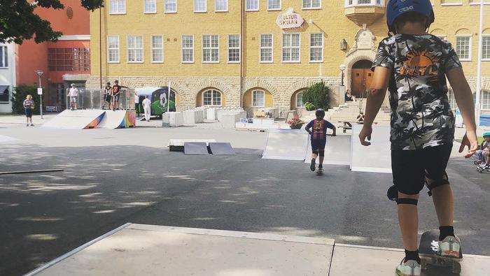Barn som åker skateboard. Kulturskolan syns i bakgrunden.